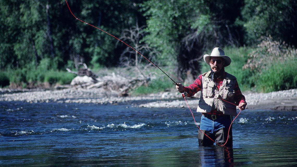 Fly fisherman casting into a Montana stream.